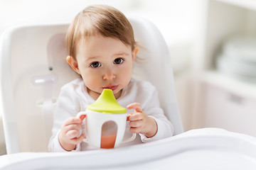 Image showing baby drinking from spout cup in highchair at home