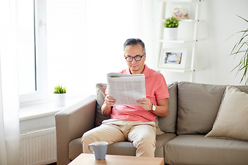 Image showing happy man in glasses reading newspaper at home