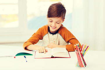Image showing smiling, student boy reading book at home