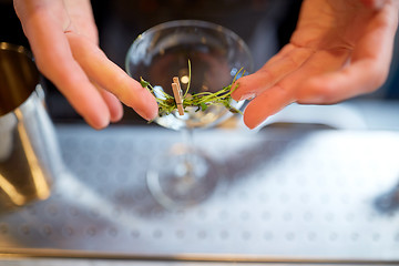 Image showing bartender decorating glass of cocktail at bar