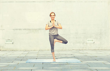 Image showing woman making yoga in tree pose on mat