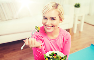 Image showing smiling young woman eating salad at home