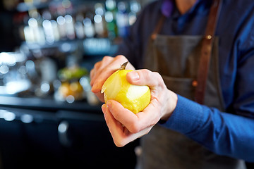 Image showing bartender removing peel from lime at bar