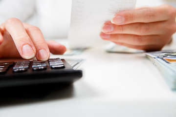 Image showing savings, finances, economy and home concept - close up of hands with calculator counting money and making notes at home