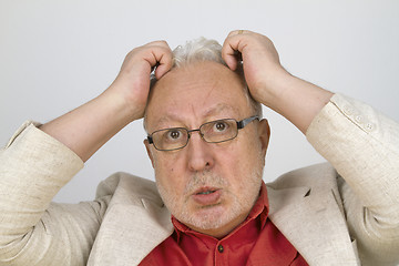 Image showing White haired senior with glasses tearing his hair