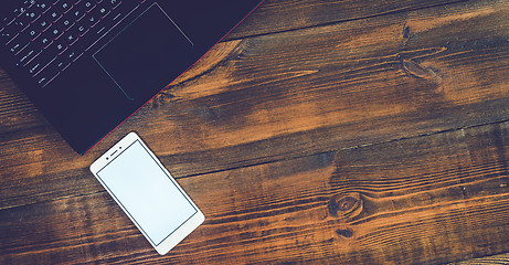 Image showing Workspace with laptop and smartphone on hard wood desk