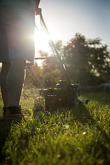 Image showing Young man mowing the grass