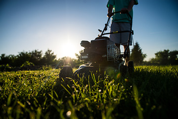 Image showing Young man mowing the grass