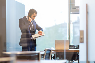 Image showing Businessman talking on a mobile phone while looking at wristwatch.