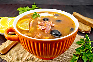 Image showing Solyanka with lemon and black olives in bowl on dark board