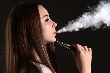 Image showing The face of vaping young woman at black studio