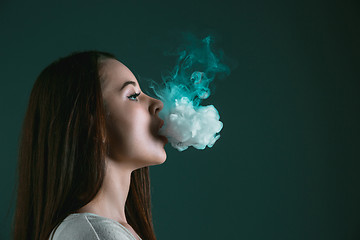 Image showing The face of vaping young woman at black studio