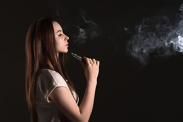 Image showing The face of vaping young woman at black studio