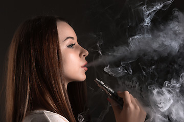 Image showing The face of vaping young woman at black studio