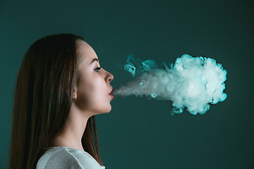 Image showing The face of vaping young woman at black studio