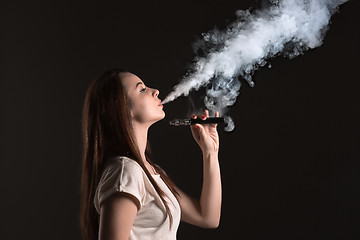 Image showing The face of vaping young woman at black studio