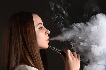 Image showing The face of vaping young woman at black studio