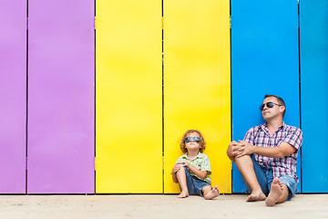 Image showing Father and son relaxing near the house at the day time.