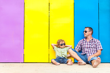 Image showing Father and son relaxing near the house at the day time.