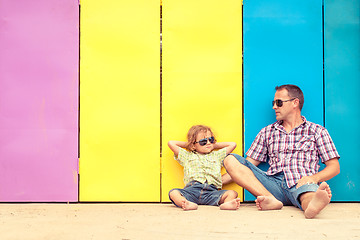 Image showing Father and son relaxing near the house at the day time.