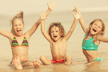 Image showing Three happy children  playing on the beach