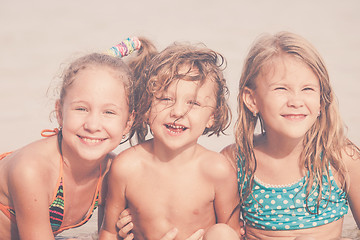 Image showing Three happy children  playing on the beach