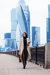 Image showing Smiling beautiful woman in a light coat against the backdrop of 