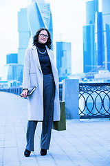 Image showing Beautiful smiling woman in a light trendy coat on the waterfront