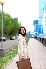 Image showing beautiful business woman in a light coat with a stylish wooden c