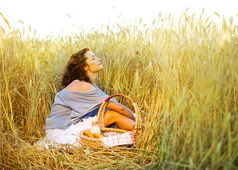 Image showing Beautiful woman relaxes in a field among wheat ears