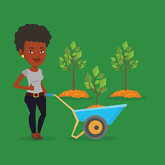 Image showing Woman pushing wheelbarrow with plant.