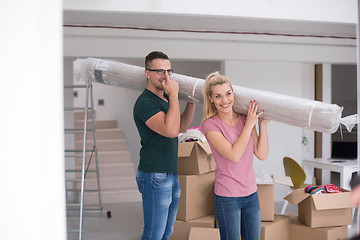 Image showing couple carrying a carpet moving in to new home