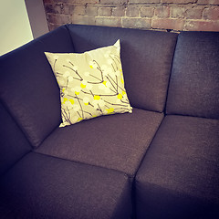 Image showing Corner sofa with cushion near brick wall