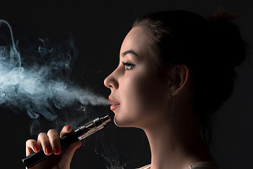 Image showing The face of vaping young woman at black studio