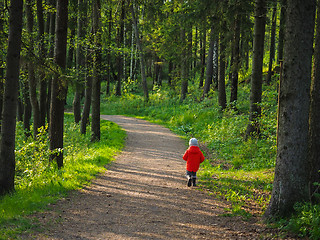 Image showing Unrecognizable little boy in a big orange jacket running along o