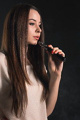 Image showing The face of vaping young woman at black studio