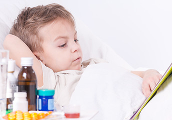 Image showing Sick boy in bed reading book