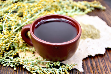 Image showing Tea with wormwood in clay cup on paper