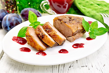Image showing Duck breast with plum sauce and basil in plate on board