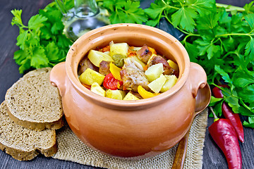 Image showing Roast meat and squash in clay pot on dark board