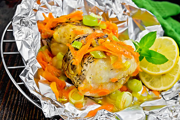 Image showing Pike with carrots and basil in foil on dark board