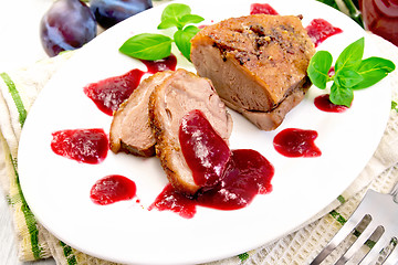 Image showing Duck breast with plum sauce in plate on board