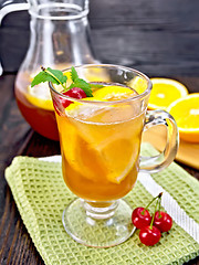 Image showing Lemonade with cherries in wineglass and jug on dark board