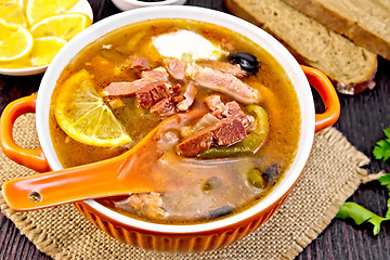 Image showing Solyanka with lemon and black olives in bowl on board