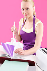 Image showing Young, attractive housewife cooks food in a pink kitchen 