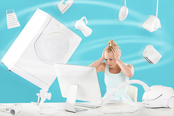 Image showing Purchasing power vertigo - online shopping . A woman sits in front of a computer monitor and fly above it everyday appliances 