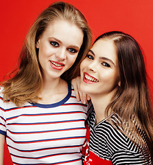 Image showing two best friends teenage girls together having fun, posing emotional on red background, besties happy smiling, lifestyle people concept close up