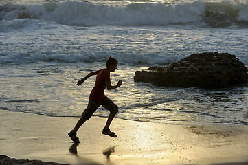 Image showing Boy runs along the seashore