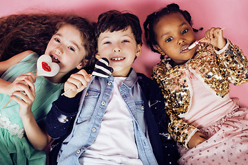 Image showing lifestyle people concept: diverse nation children playing together, caucasian boy with african little girl holding candy happy smiling closeup