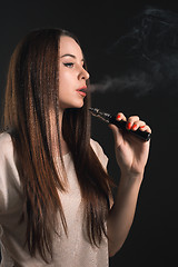 Image showing The face of vaping young woman at black studio